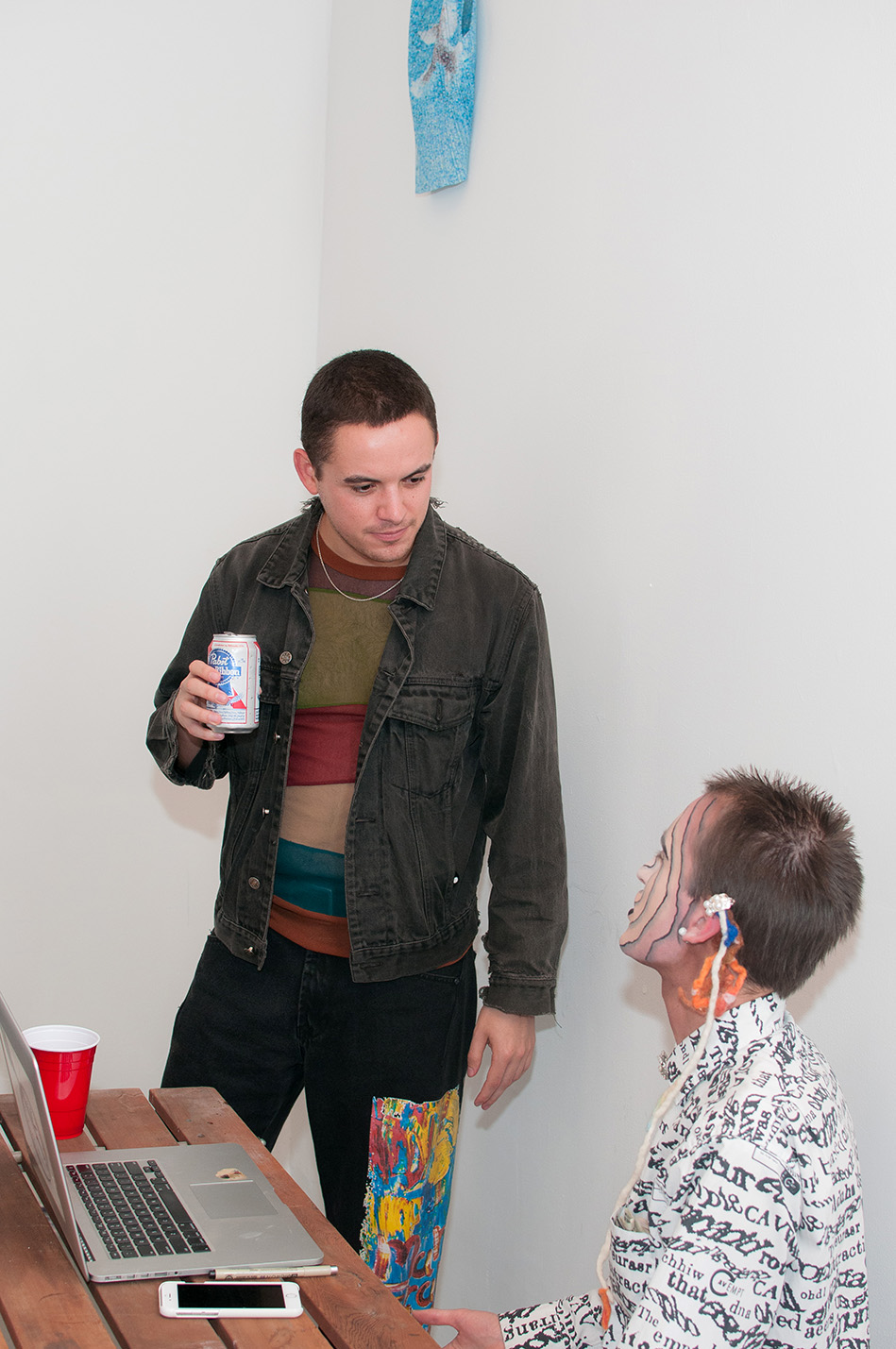 Two people chatting under a tank top hung on the wall